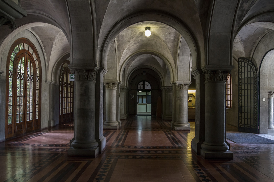 Fotografía del hall del Campus Oriente UC, se ven varios pasillos hechos por gruesas columnas de piedra
