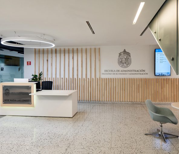 Fotografía de la Escuela de Administración Pública UC por dentro, se ve un mesón y el nombre de la Escuela al fondo