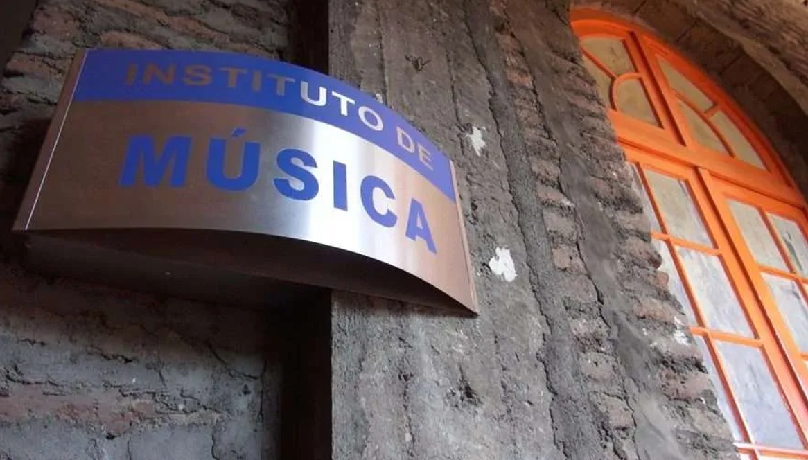 Fotografía de una pared de cemento con una ventana roja y un cartel escrito Instituto de Música