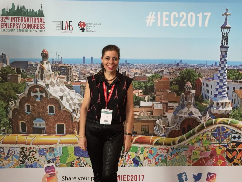 Fotografía de la egresada UC, Keryma Acevedo, con el afiche de un Congreso de fondo