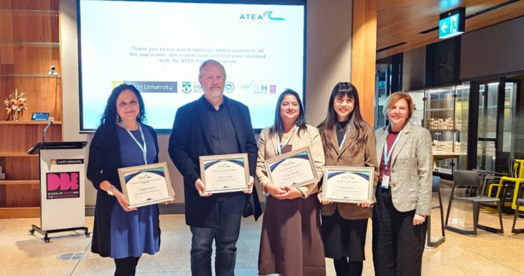 Fotografía de un grupo de cinco personas posando en una ceremonia, sosteniendo certificados.