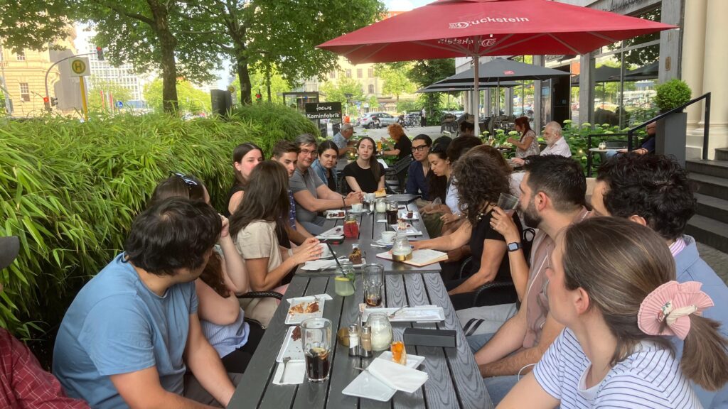 Grupo de personas sentadas alrededor de una mesa en una terraza.