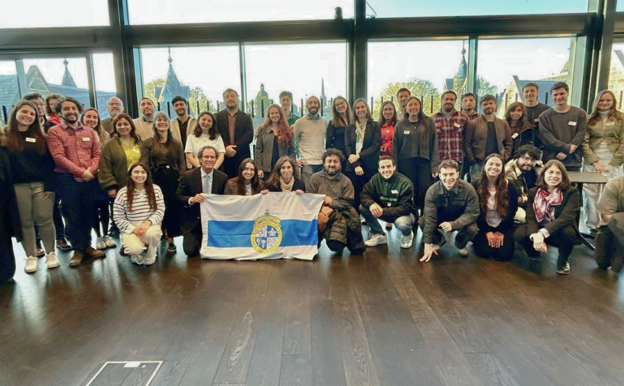 Fotografía de un grupo de decenas de personas al centro algunas sosteniendo la bandera de la Universidad Católica