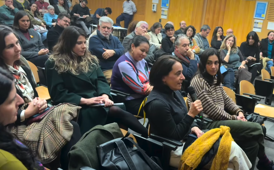 Fotografía de decenas de personas en un auditorio una de ellas con un micrófono